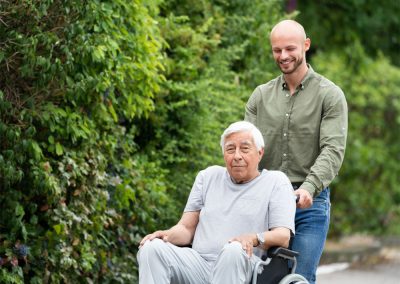 A man being wheeled outside by his caregiver